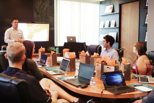 man standing in front of people sitting beside table with laptop computers